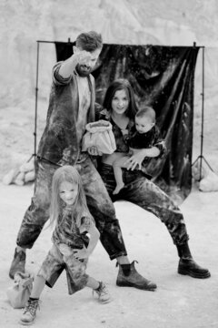 young family with 2 kids dressed in black clothes posing for a photo during a stylized photo shoot in a natural white location, fun, stylish and charismatic. Family with two daughters