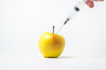 Fruit genetic modification concept. A syringe injects a chemical into an apple on a white background. Junk food