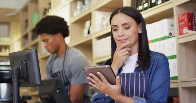 Animation of thoughtful biracial waitress using tablet in coffee shop