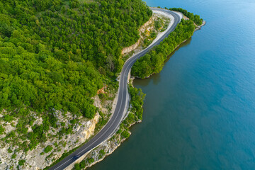 Aerial view of an amazing road on the coast line next to a river. Beautiful roads infrastructure around the world during a beautiful summer day. © Dragoș Asaftei