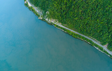 Aerial view of an amazing road on the coast line next to a river. Beautiful roads infrastructure around the world during a beautiful summer day.