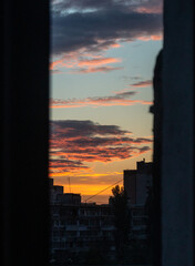 Fototapeta na wymiar Orange sunset over the buildings. Pink clouds in evening sky