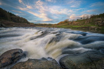 Waterfall over a dam in the Minho river at sunset