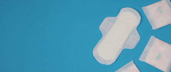 Woman sanitary napkins on blue background. Top view. Absorbent pads worn by women to absorb menstrual blood. Comfortable white sanitary napkins arranged on light blue paper. Represent Hygiene concept