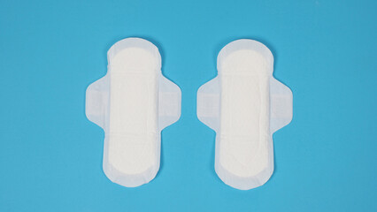 Woman sanitary napkins on blue background. Top view. Absorbent pads worn by women to absorb menstrual blood. Comfortable white sanitary napkins arranged on light blue paper. Represent Hygiene concept © gnepphoto