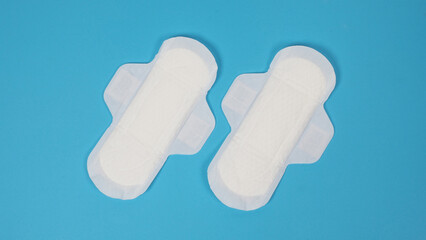 Woman sanitary napkins on blue background. Top view. Absorbent pads worn by women to absorb...