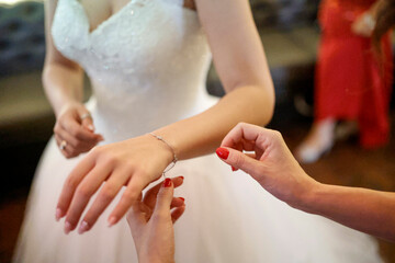 Dettaglio di mani in cui un amica aiuta una sposa a prepararsi per il matrimonio