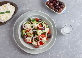 Traditional drink Ouzo or Raki and traditional greek salad, tzatziki and olives