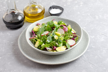 Fresh vegetarian vegetable salad with radish, cucumber, arugula, onion and cherry tomato. Olive oil and balsamic vinegar. Healthy food, top view.
