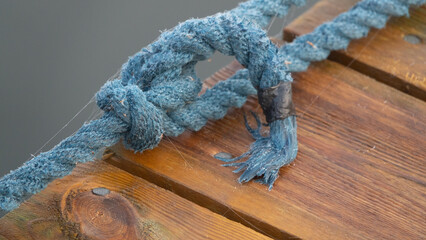 blaues Tau verknotet an einem Steg aus Holz, straff gespannt