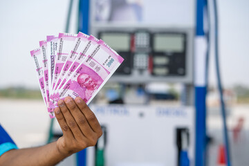 Close up shot of, fuel station worker hands counting money at petrol pump - concept of business...