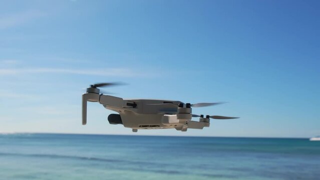The silhouette of the drone flies against the background of the ocean, the sea. Modern technologies for shooting photos and videos from above. Sunset, sunrise. Drone with illumination in sunlight