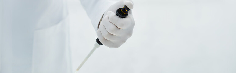 partial view of scientist in latex glove holding micropipette, banner.