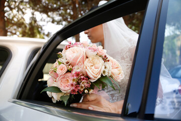 bouquet di fiorini primo piano e sposa che entra in auto per andare a sposarsi 