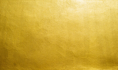 Obraz premium Gold wall texture background. Yellow shiny gold foil paint on wall sheet with gloss light reflection