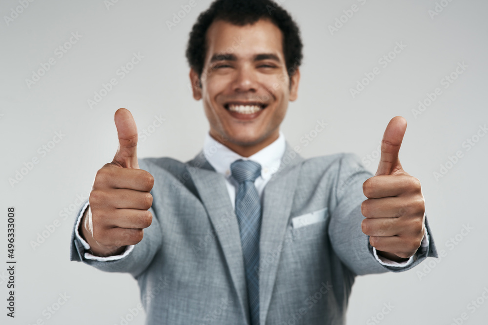 Poster i like that idea. studio shot of a confident businessman showing thumbs up while standing against a 