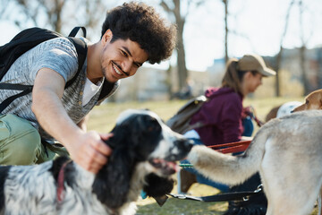 Happy male dog walker and dogs relax during a walk in park.