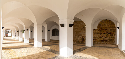 whitewashed portico with many arches and a patterned stonework floor
