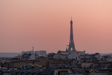 View of the stunning Eiffel Tower above the rooftops of Paris and a beautiful sunset