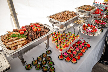 Banquet table with chafing dish heaters. Grilled meat