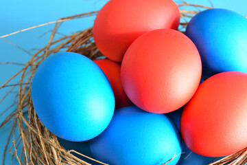 blue and red easter eggs in bird nest, close-up