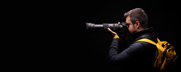 Photographer with a yellow bag is taking a photo with a black background