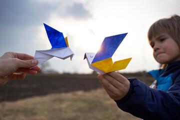 2 paper doves of peace, wings are painted in yellow - blue colors of Ukrainian flag against...