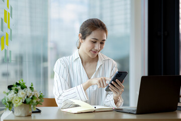 young businesswoman looking at financial information from a mobile phone, she is checking company financial documents, she is a female executive of a startup company. Concept of financial management.
