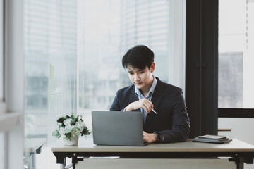 Asian man working in office at his company, Asian businessman checking on laptop in private office, executive room, young startup company executives. Management concept of startup company.