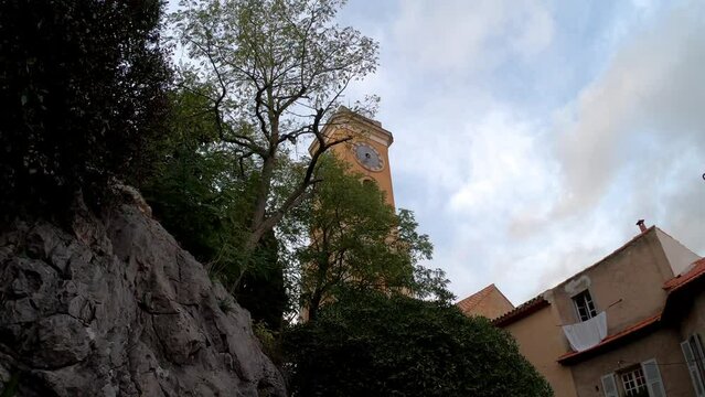 SLOW MOTION SHOT - The belfry of the Church of Notre Dame de l'Assomption (Notre-Dame-de-l'Assomption) in Eze, France. A Baroque church nestled in the medieval village.