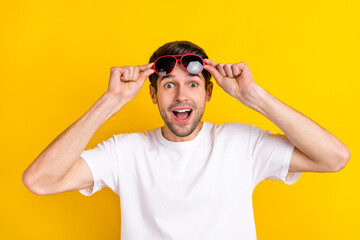 Naklejka premium Photo of impressed millennial brunet guy wear spectacled white t-shirt isolated on yellow color background