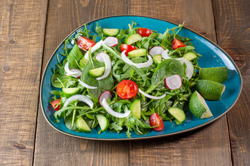 Fresh salad mix of baby spinach 
cucumber, onion, cherry tomatoes, arugula leaves and green lemon. Healthy food. Vegan breakfast, vegetarian food.