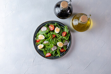 Salad with cherry tomatoes, fresh arugula and quail egg. Concept for a tasty and healthy meal. Vitamins in vegetables and herbs for immunity against the virus. Top view. Copy space