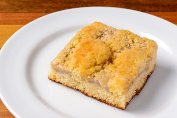 Slice of banana cake on a white plate on a wooden table.