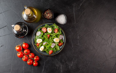 Salad with cherry tomatoes, fresh arugula and quail egg. Concept for a tasty and healthy meal. Vitamins in vegetables. Top view. Flat lay, copy space