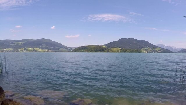incredible lake in austria named mondsee with mountains, waving reeds and wavy water a sunny day with a blue sky all in all a georgous summer day