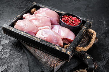 Raw Boneless and skinless Chicken leg thigh fillet with herbs. Black background. Top view