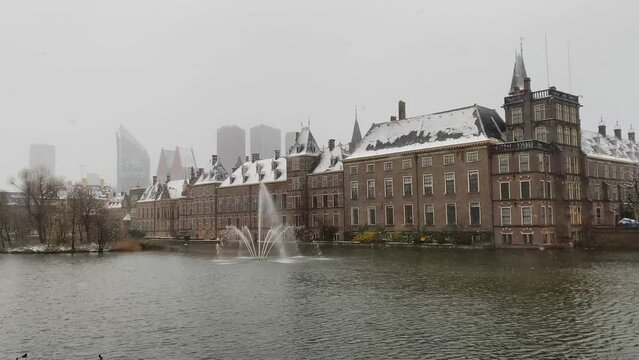 Binnenhof Palace in The Hague or Den Haag and Hohvijfer canal during winter snow in The Netherlands.