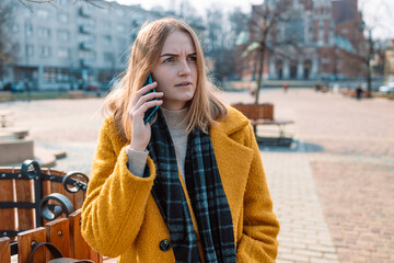 Angry young woman holding mobile phone having problems with digital device, feels angry and annoyed. Discharged broken not working and out of order gadget concept