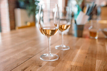Two glass of white wine on a wooden table at cafe or restaurant. 