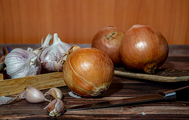 Fresh garlic bulbs and a garlic press on an old wooden board and a burlap backing.
