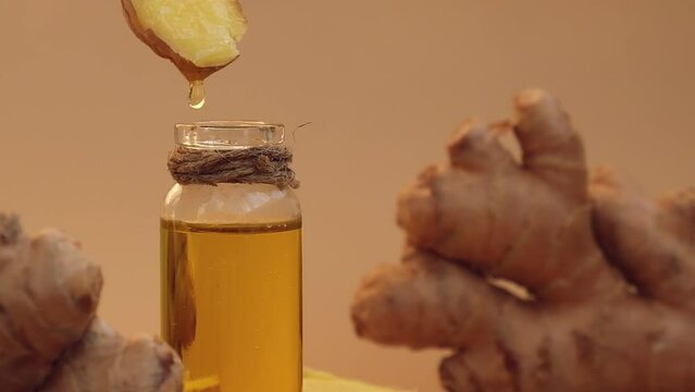 Glass bottle of essential ginger oil, ginger root on beige background. Healthy food eating concept. Zingiber officinale Essential oil. Earth tones Natural cosmetics ingredients for skincare, body 