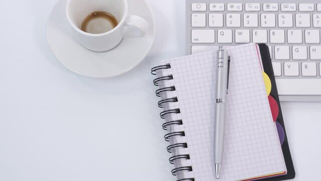 White office table with keyboard, notebook, pen and coffee cup
