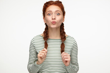  sending air kiss into cameraportrait of young ginger female standing over white studio background