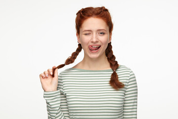 portrait of young ginger female standing over white studio background lick her lip and wink