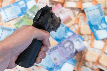 Holding a gun and pointing towards a background of chilean banknotes.