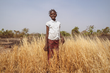 Young African Village Girl standing in a field while helping in her family cultivation.Rural landscape.