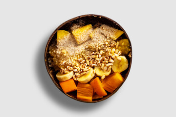 Healthy fruit bowl in a coconut shell. Fresh sliced fruits and puffed corns is a tasty meal. Natural food prepared delicious. Vegan lifestyle with many different ingredients.