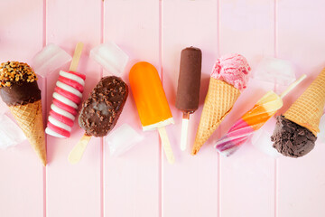 Assorted chocolate and colorful summer frozen treats. Above view  scattered on a pink wood...