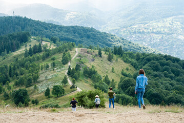 Four women come down the mountain. Tourists inspect the picturesque mountain landscape. Mountain trail along the ridge. Ukrainian Carpathians. 